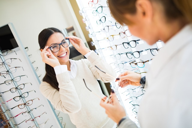 Young woman trying on glasses in an eye doctor's office.