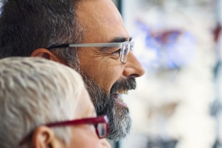 Man and woman smiling, wearing glasses.