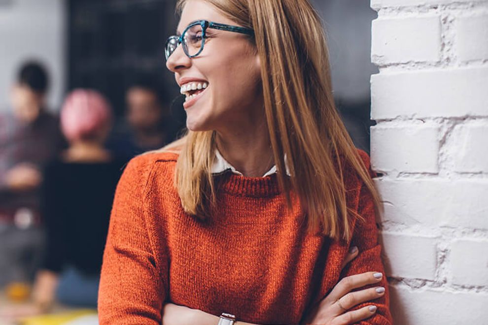 A young professional woman wearing glasses and smiling.