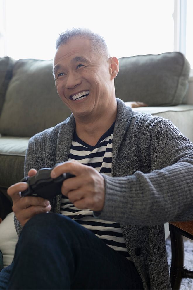 Middle aged man playing a video game and smiling.