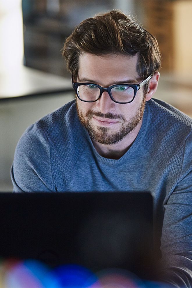 man in glasses looking at laptop 