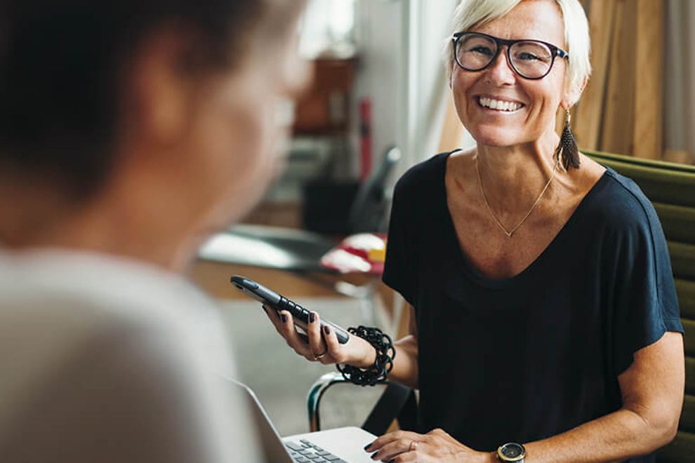 Two women in an office setting, one is smiling.