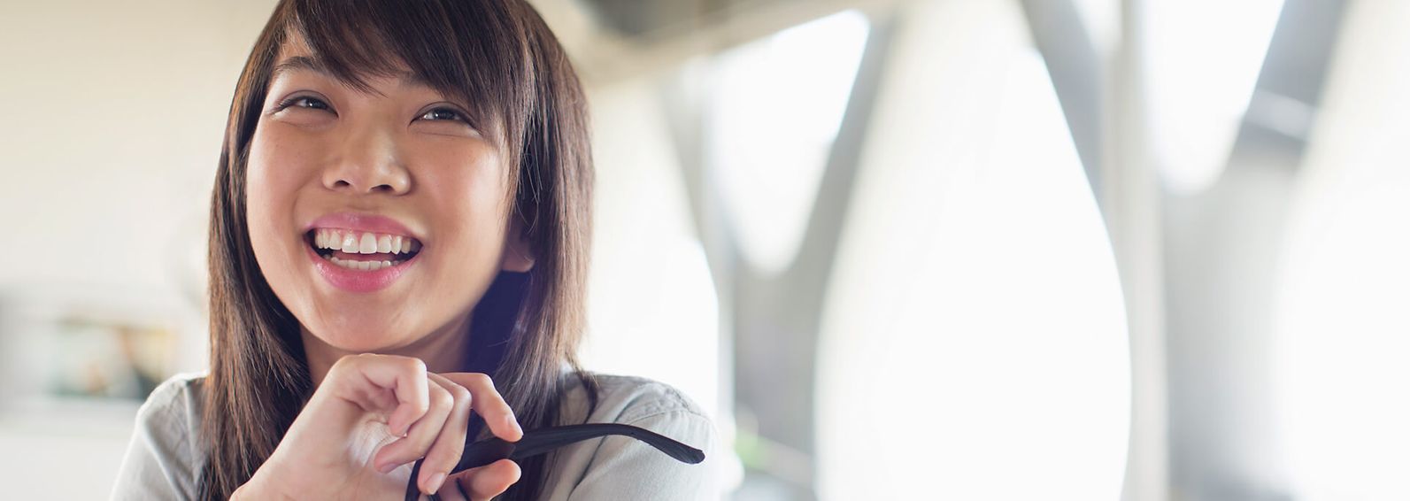 Young woman smiling and holding glasses.