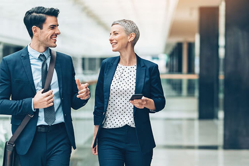 Two colleagues, a man and woman, walking and talking.