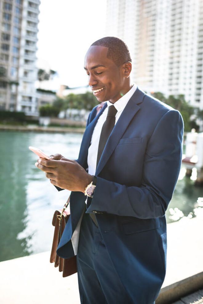 Businessman using a smartphone by a canal.