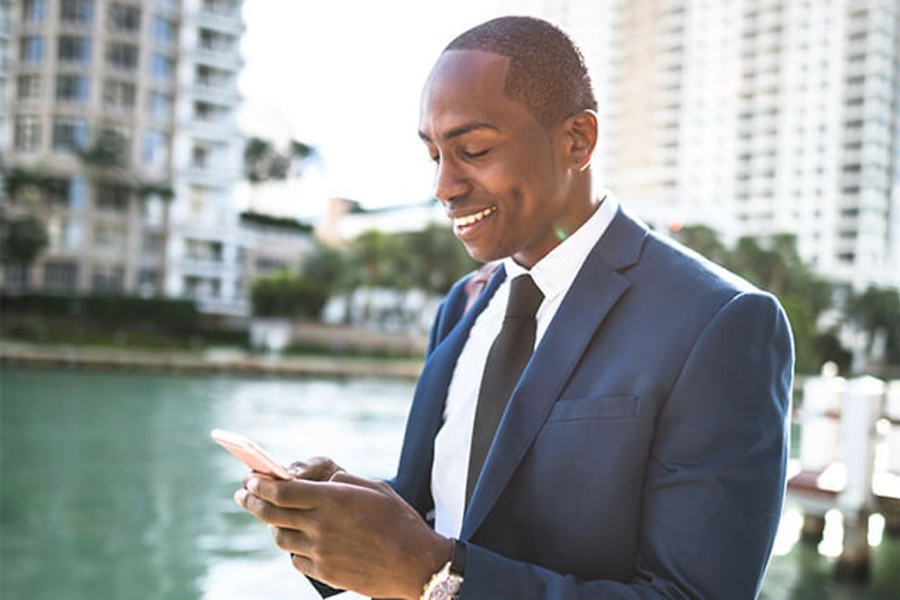 Businessman using a smartphone by a canal.