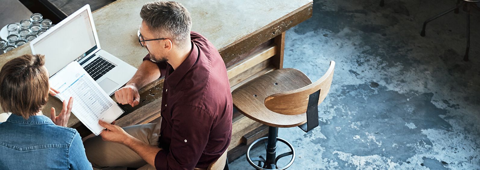 Man and woman reviewing business documents in a restaurant.