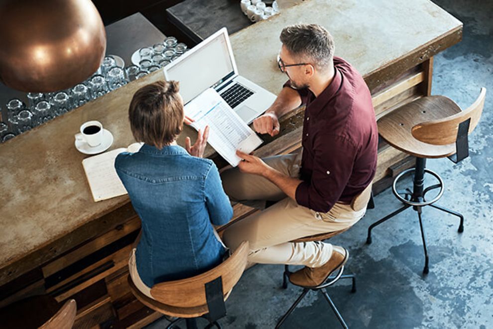 Man and woman reviewing business documents in a restaurant.