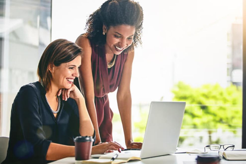 Two women looking at a laptop in an office.