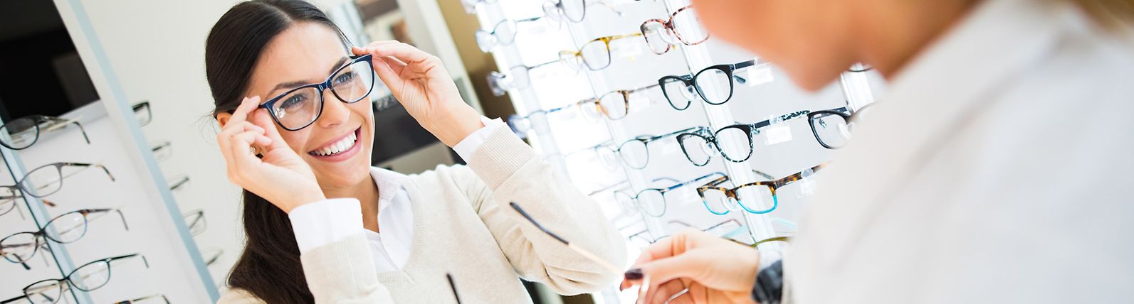 Young woman trying on glasses in an eye doctor's office.