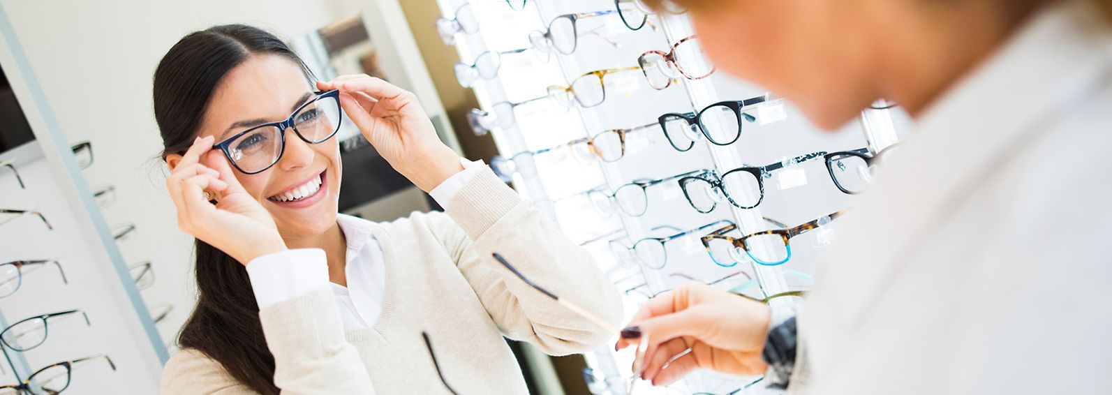 Young woman trying on glasses in an eye doctor's office.