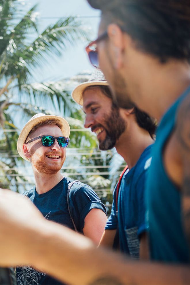 Young men wearing sunglasses with palm trees in the background.