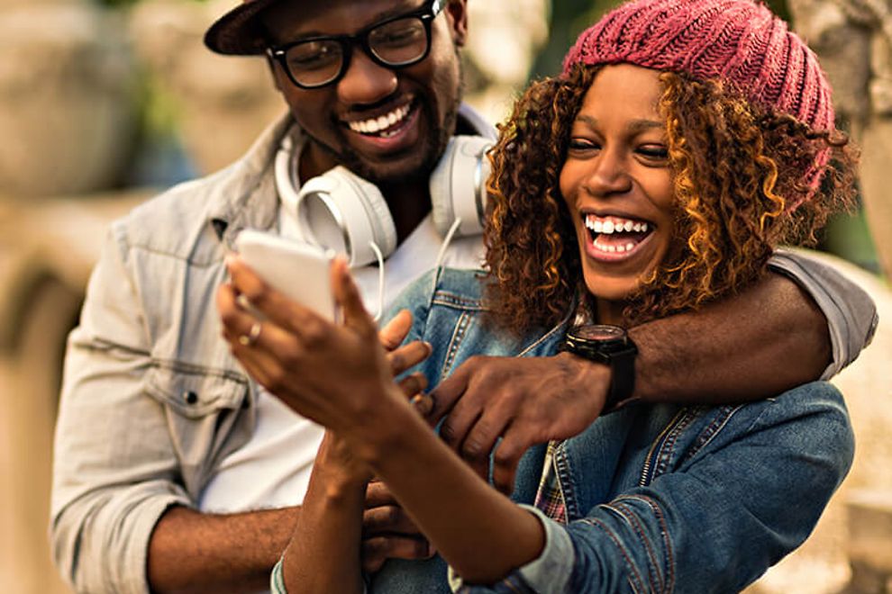 man and woman laughing looking at phone screen