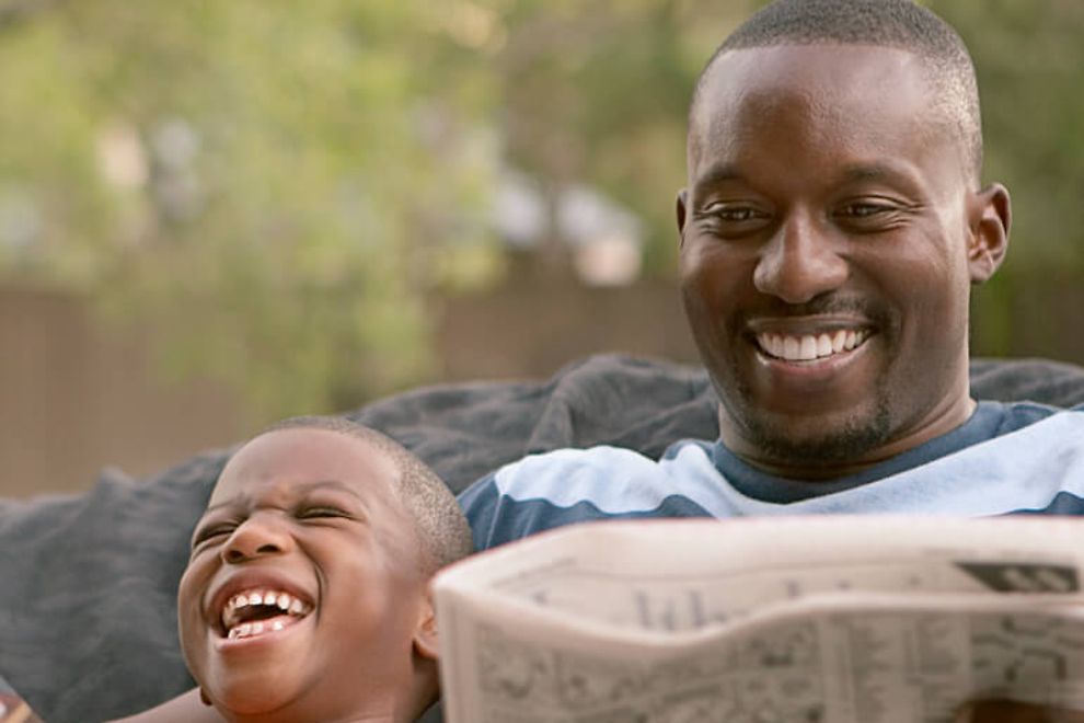 father and son reading and laughing