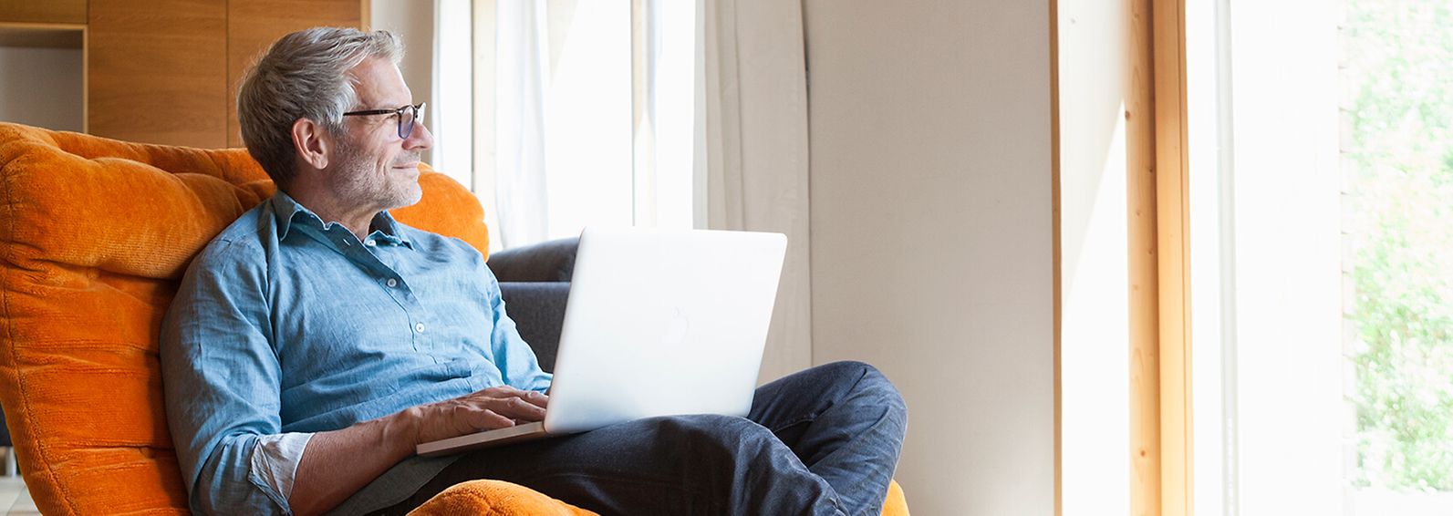 Middle-aged man sitting in a chair using a laptop.