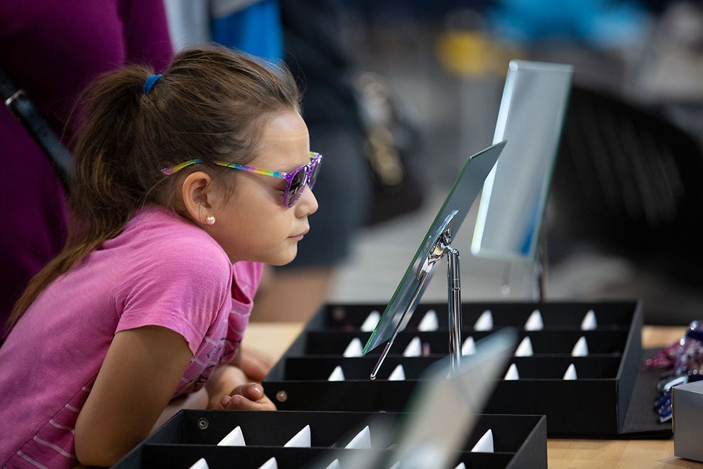 young girl trying on glasses at vision clinic