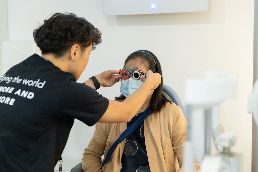 person giving eye exam to woman in eye doctor chair