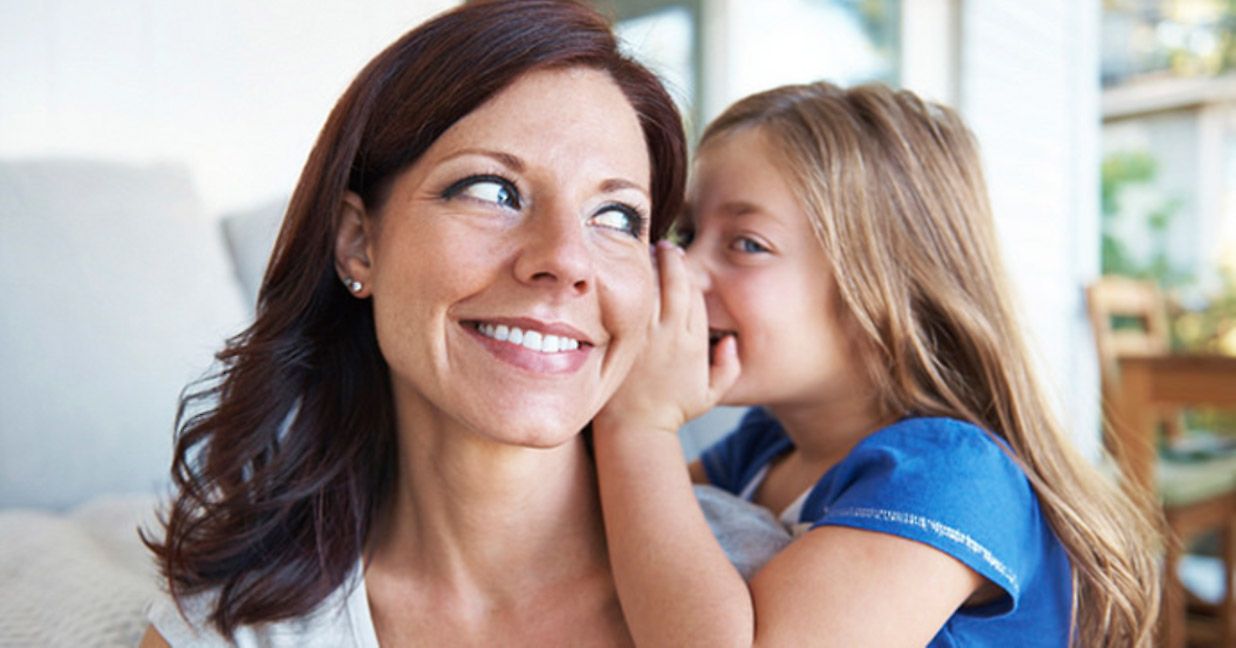 daughter whispering into mother's ear